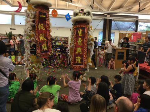 Asian American Heritage Month celebration with children sitting down as they watch dragon dance performance at library