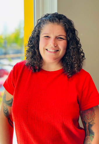 woman in red top with curly shoulder length hair.