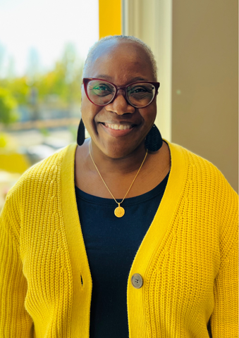 woman in black top with yellow seater and glasses. 