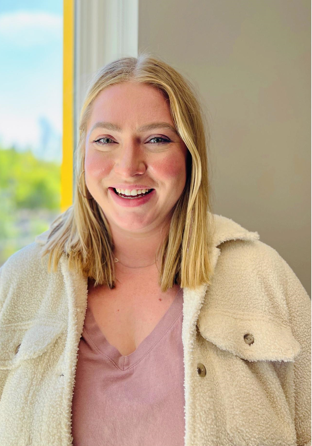 woman with blonde hair, tan jacket and pink top