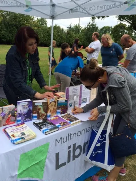People interact at a table displaying books during a Slavic Festival in 2016. Photo credit: Multnomah County Library