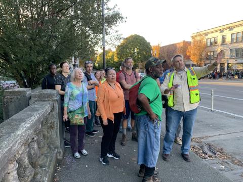 Group of people at the west bank of the Burnside Bridge being given a tour.