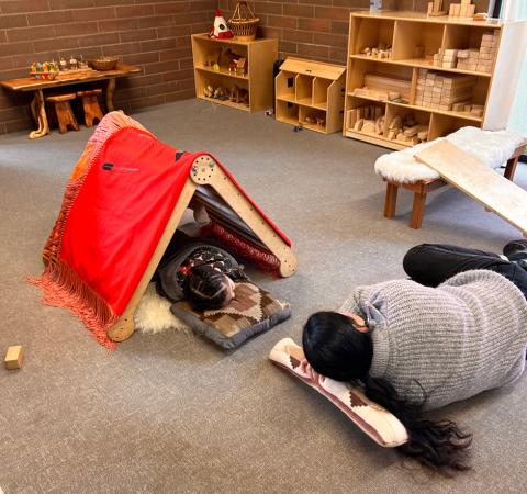 Native child and caregiver napping together at a Chaku Manaqi łush play circle