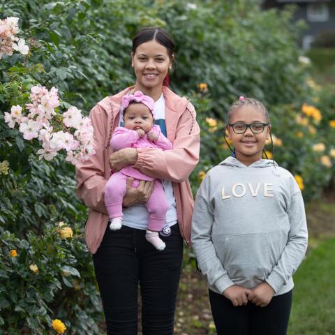 Portrait of a young black mom, baby and daughter in a rose garden 