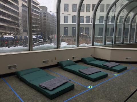 cots are lined up under a window covered on the outside with snow