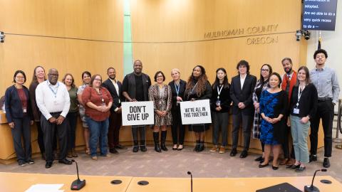 A photo in the Multnomah County Board room with JVP, board members, staff, and community members.