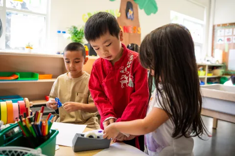 Preschool students working together on a craft
