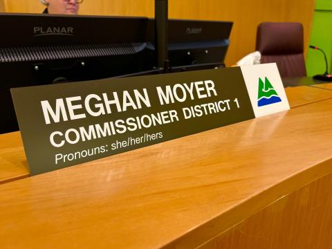 Dias name plate reading Meghan Moyer Commissioner District 1, Pronouns: she/her/hers