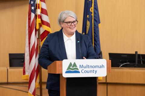 Commissioner Meghan Moyer standing at a speakers podium.