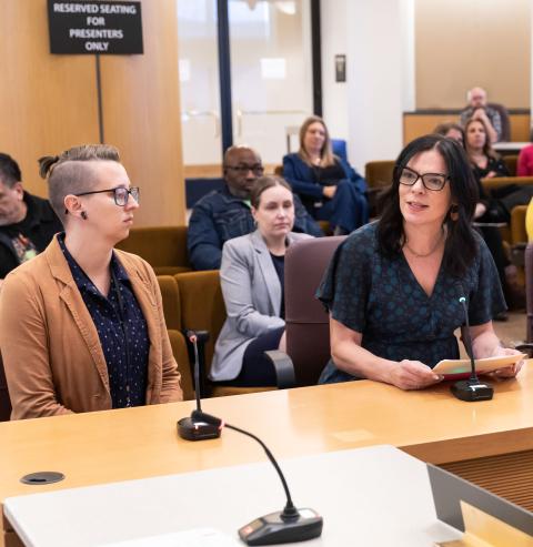 DCJ Director Denise Pena speaks at a Multnomah County proclamation ceremony with Nichelle Moore of Victim and Survivor Services sitting alongside