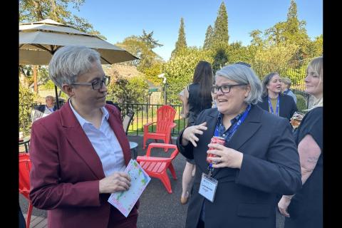 This is a photo of Governor Tina Kotek and Commissioner Meghan Moyer talking together and an outdoor event.