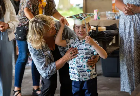 A preschool provider hugs a student at a PFA graduation ceremony