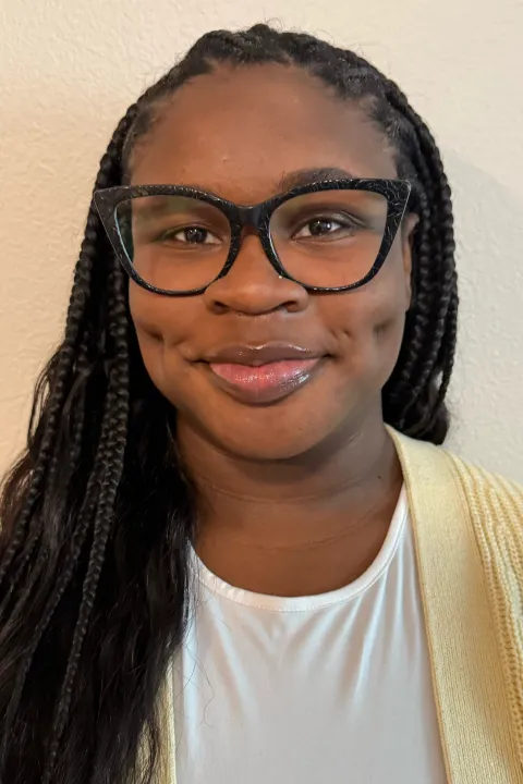 Jada smiling in a white shirt with a yellow sweater