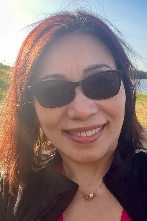 Kimlien smiling in sunglasses wearing a black sweater