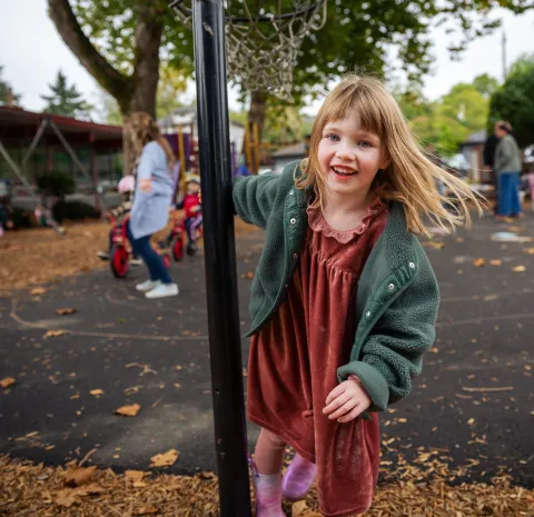 young child playing in a playground with leaves on the ground