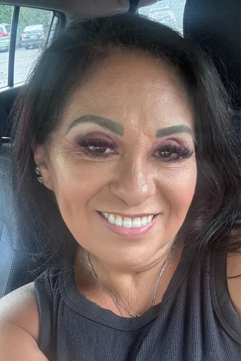 Melinda smiling with a black top on, sitting in a car