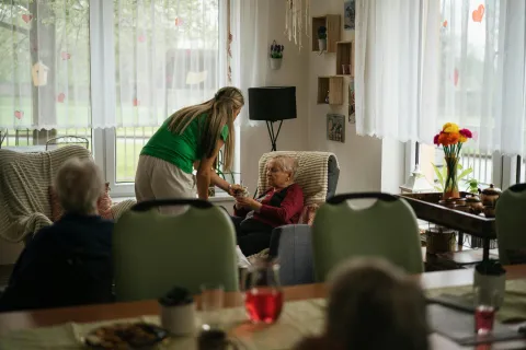 adult care home caregiver hands out drinks to residents