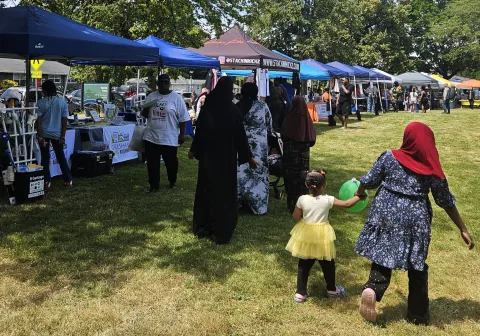 A woman in a hijab walking away from the camera holding a young child's hand