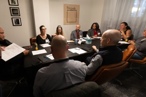A group of people sits around a table, including Jessica Vega Pederson, Mayor Keith Wilson and Commissioner Shannon Singleton 