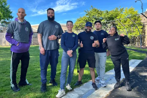 Six juvenile detention staff in a recreation yard smiling for camera