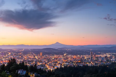Feathery clouds rise over Mt Hood and the Portland skyline at dawn.