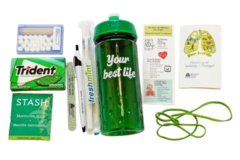 A tobacco quit kit featuring a bottle, spearmint gum, mints, tea, travel toothbrush, bookmarks and rubber bands.