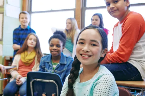 Alumnos felices sonríen en un aula.